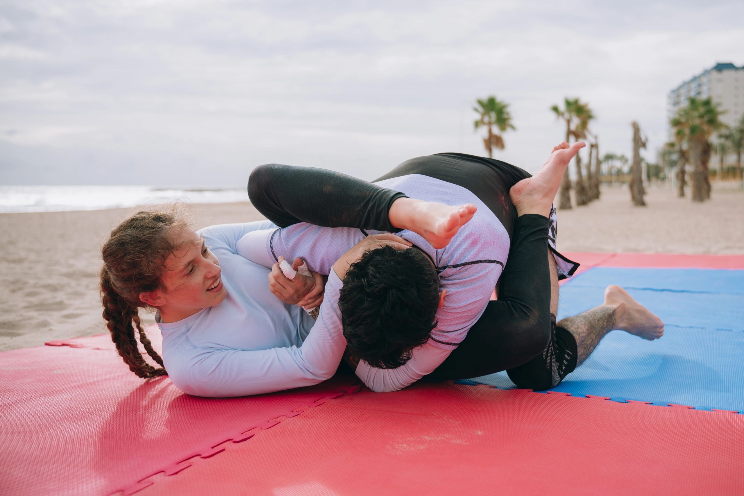 Two athletes practicing grappling technique on mats