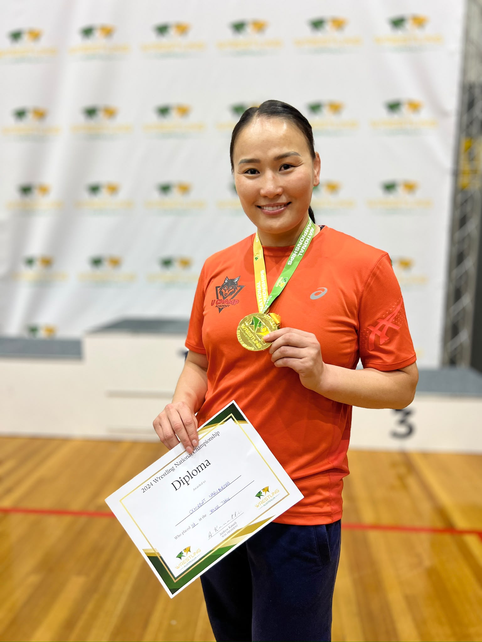 Coach Uka holding her 2024 Australian National Championship medal and certificate