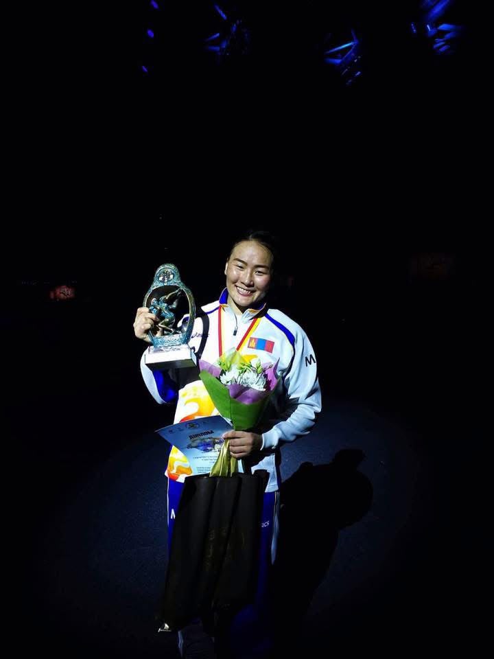 Coach Uka holding a trophy and flowers
